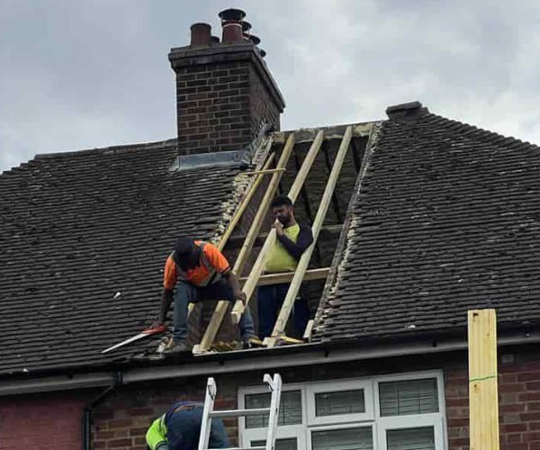 This is a photo of a roof repair being carried out. A section of the roof has been stripped and two roofers are replacing the rafters. Works being carried out by WBN Roofing Rossington